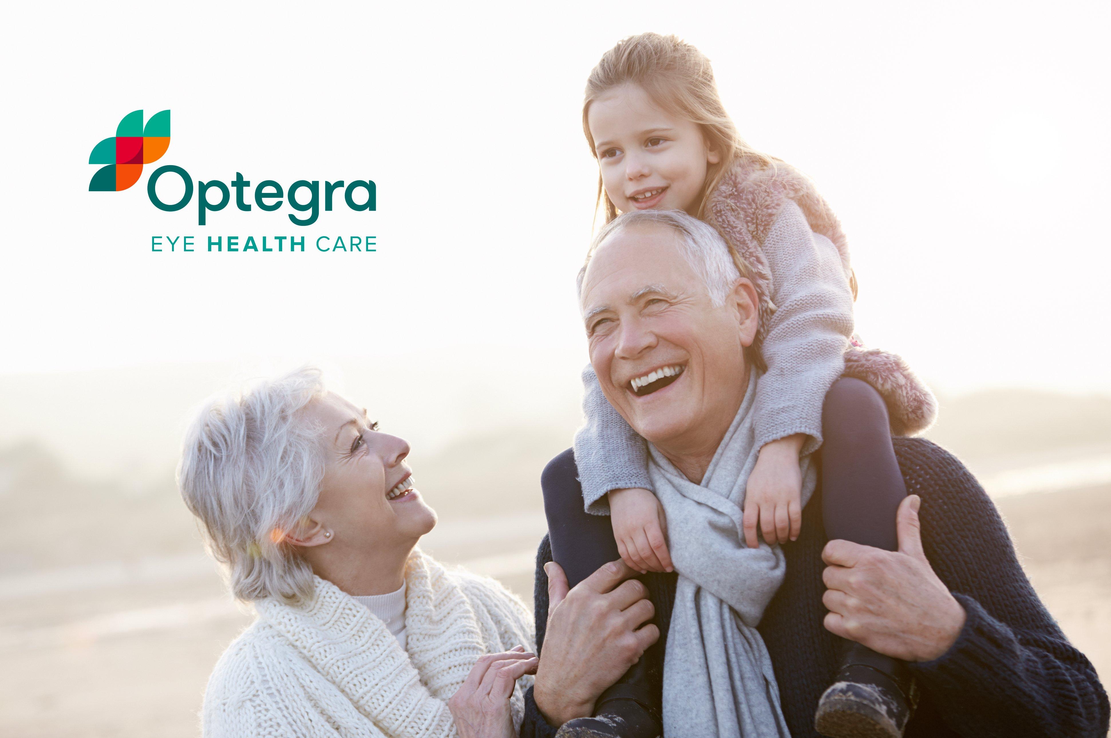 A photo of an older couple enjoying a beach walk with their grand daughter on the husband's shoulders