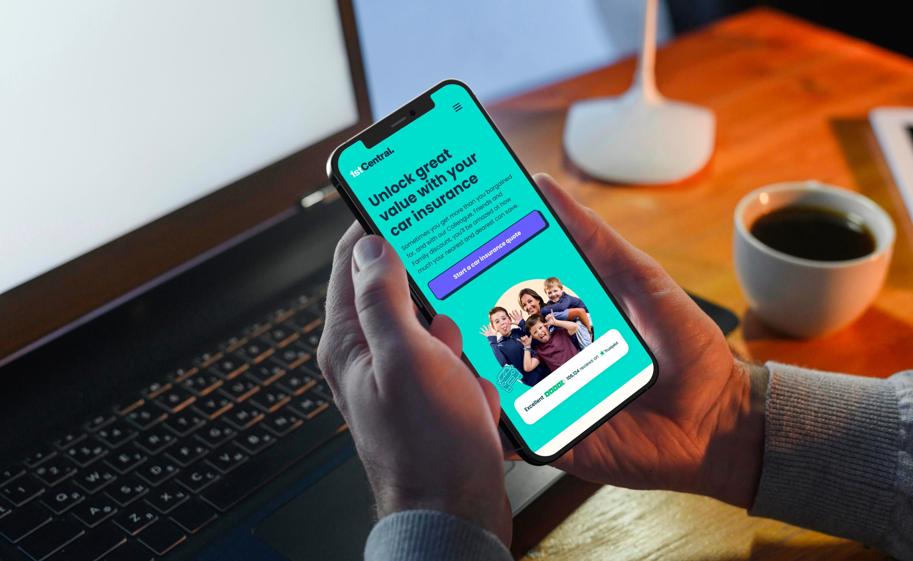 A person at a desk with the 1st Central Insurance site on his phone