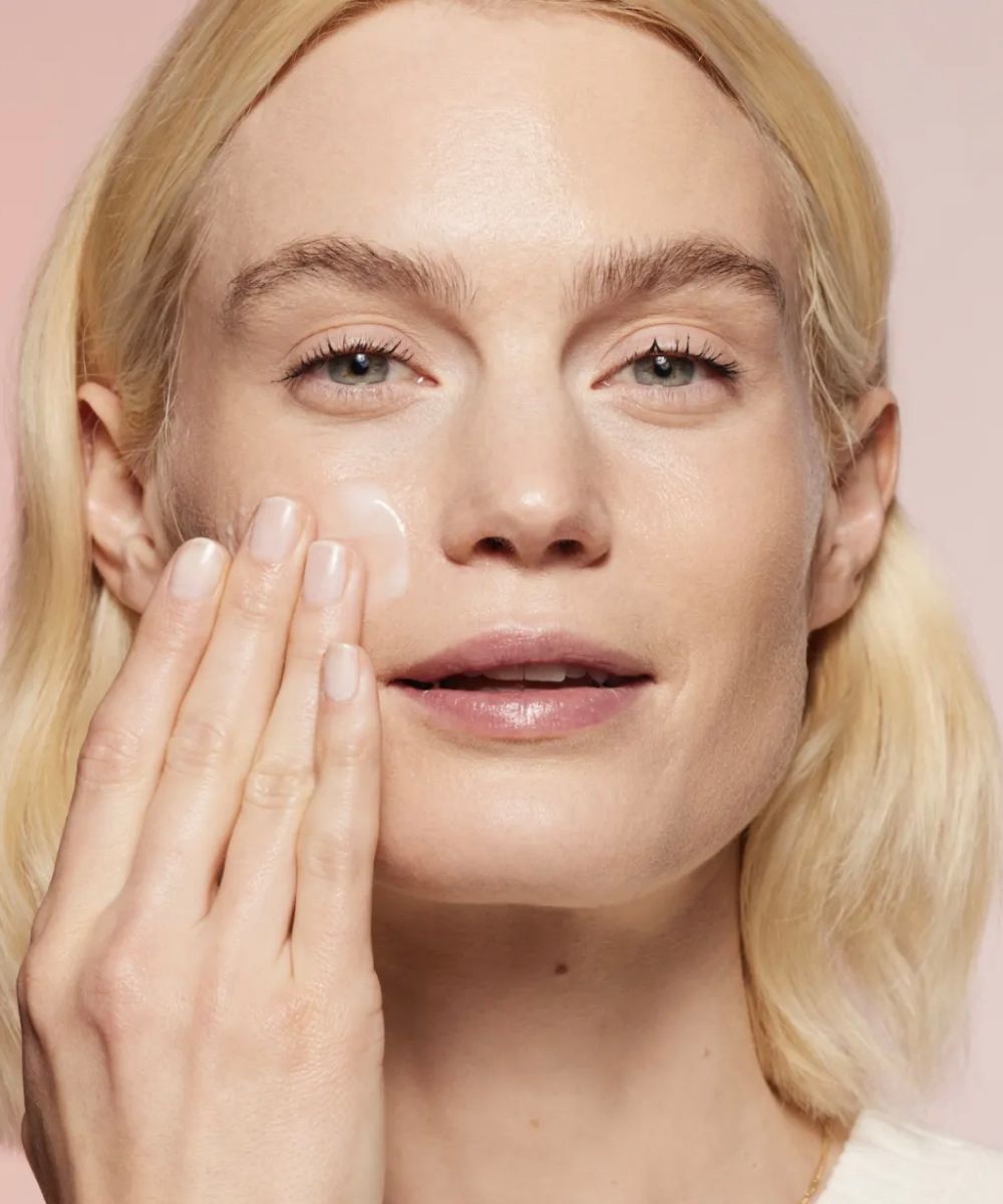 Woman with blonde hair using face serum