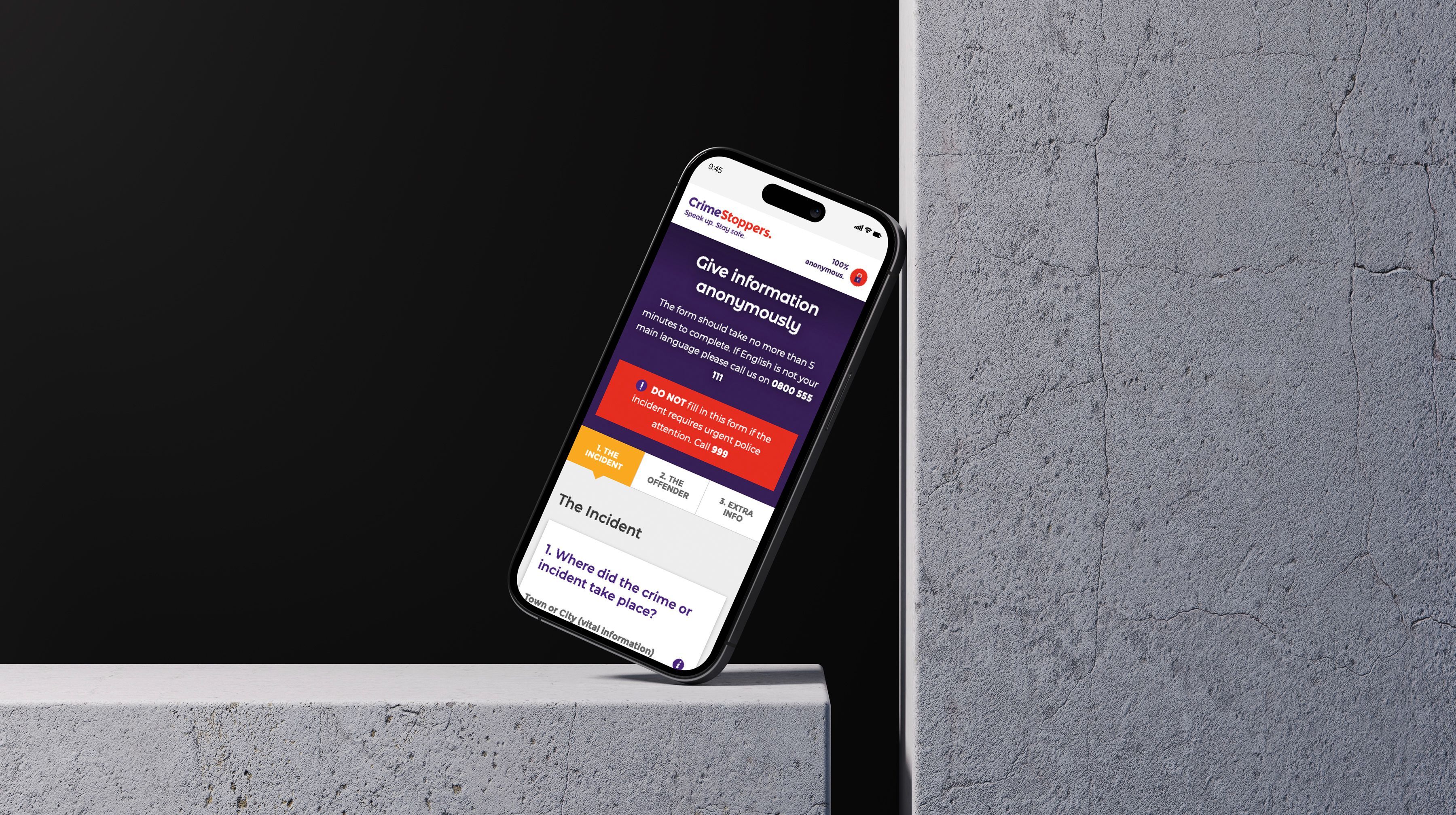 A mockup of a phone showing the report crime page, leaning against a concrete wall